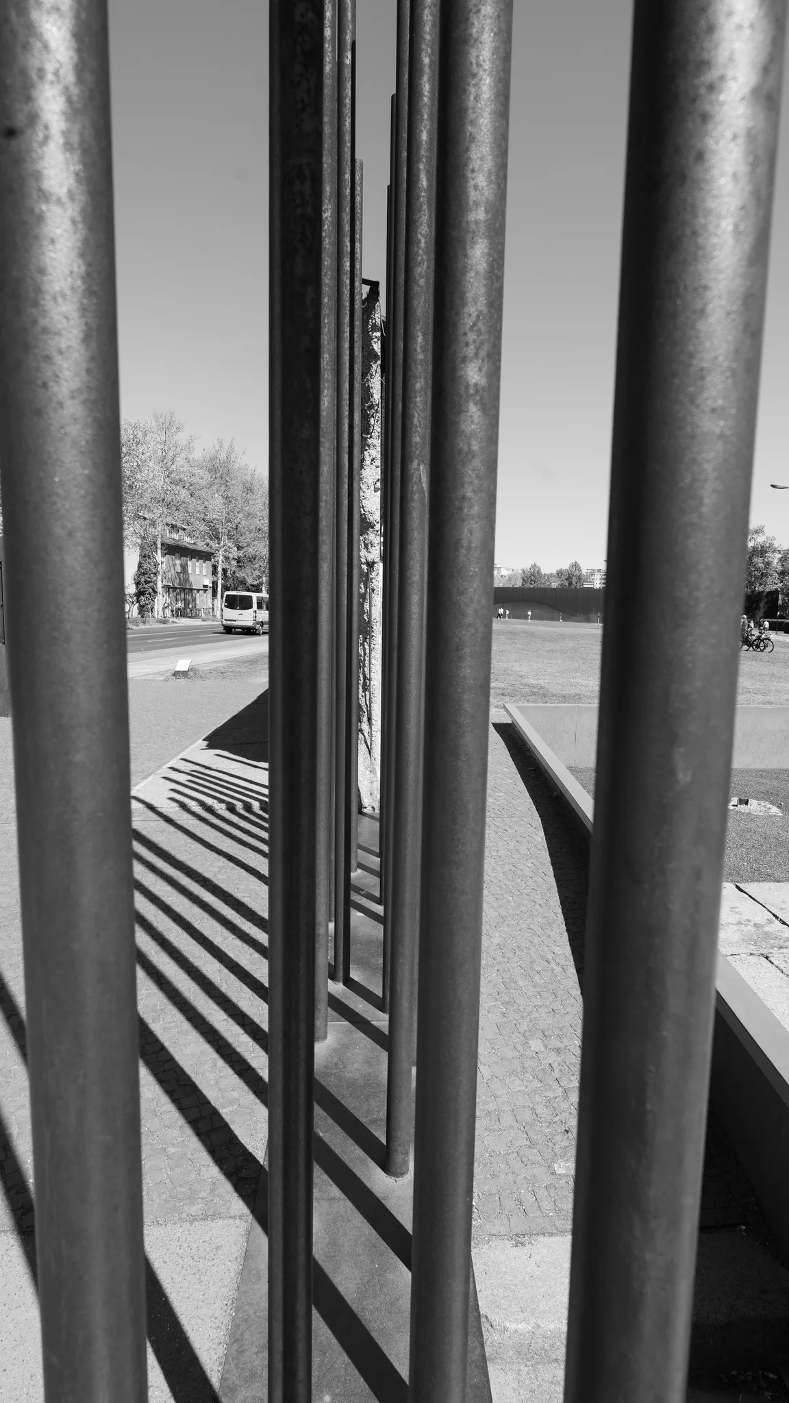 Black-and-white view through the steel rods that mark the line of the Berlin Wall at the memorial