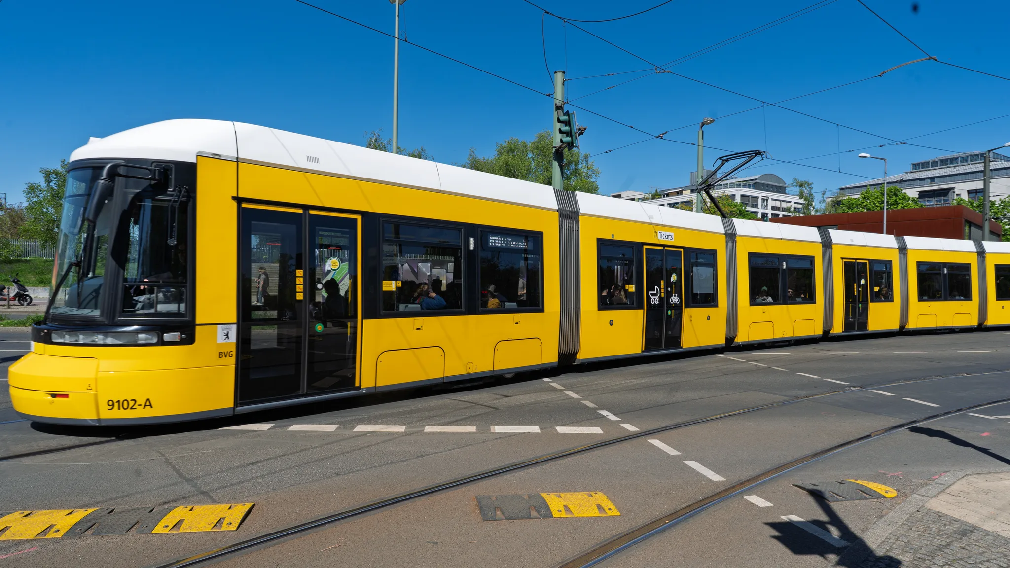A yellow Berlin tram crossing a junction on a sunny day