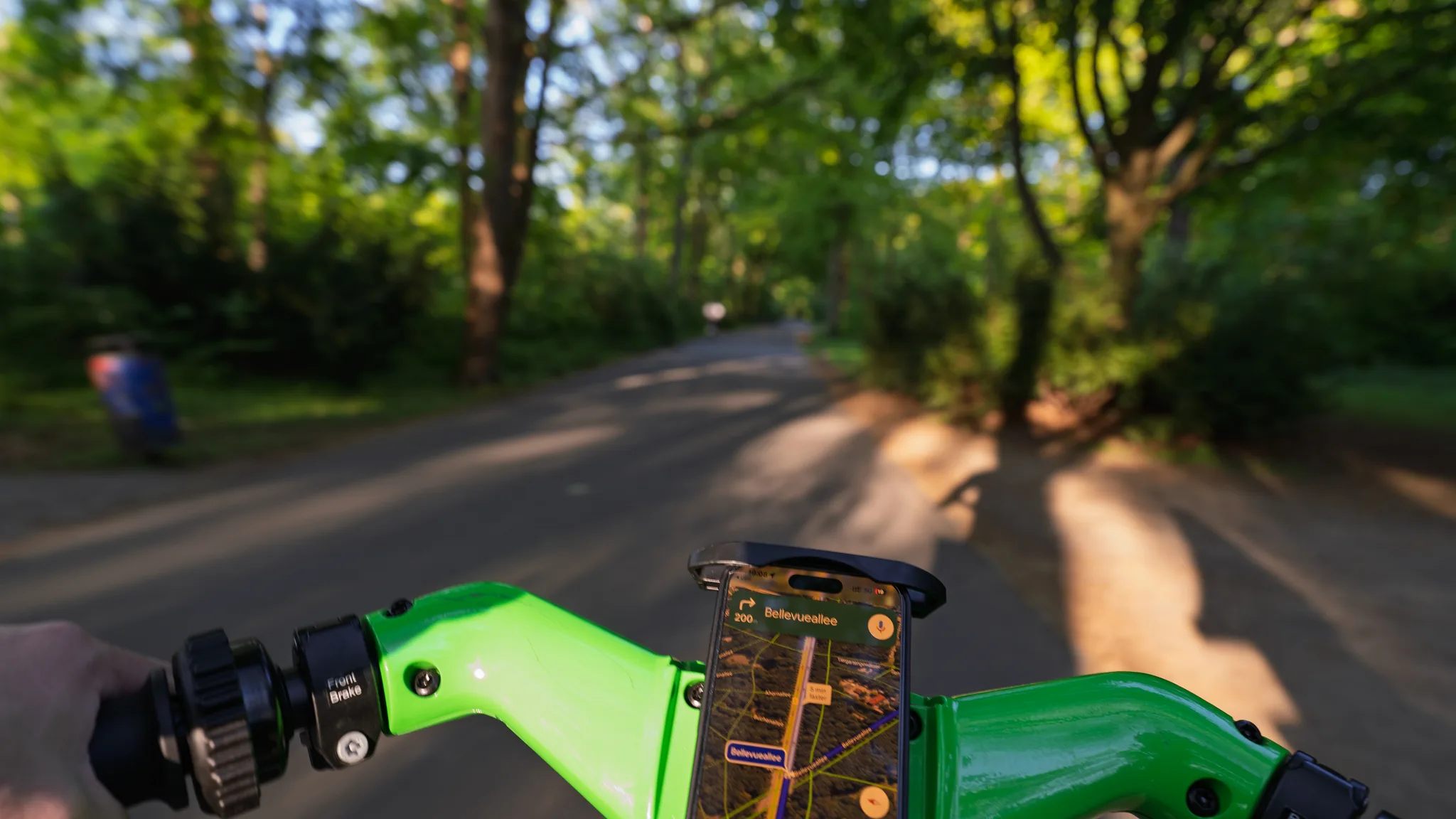 Riding a green hire bike along a tree-lined path in the Tiergarten, a map on the phone in its holder