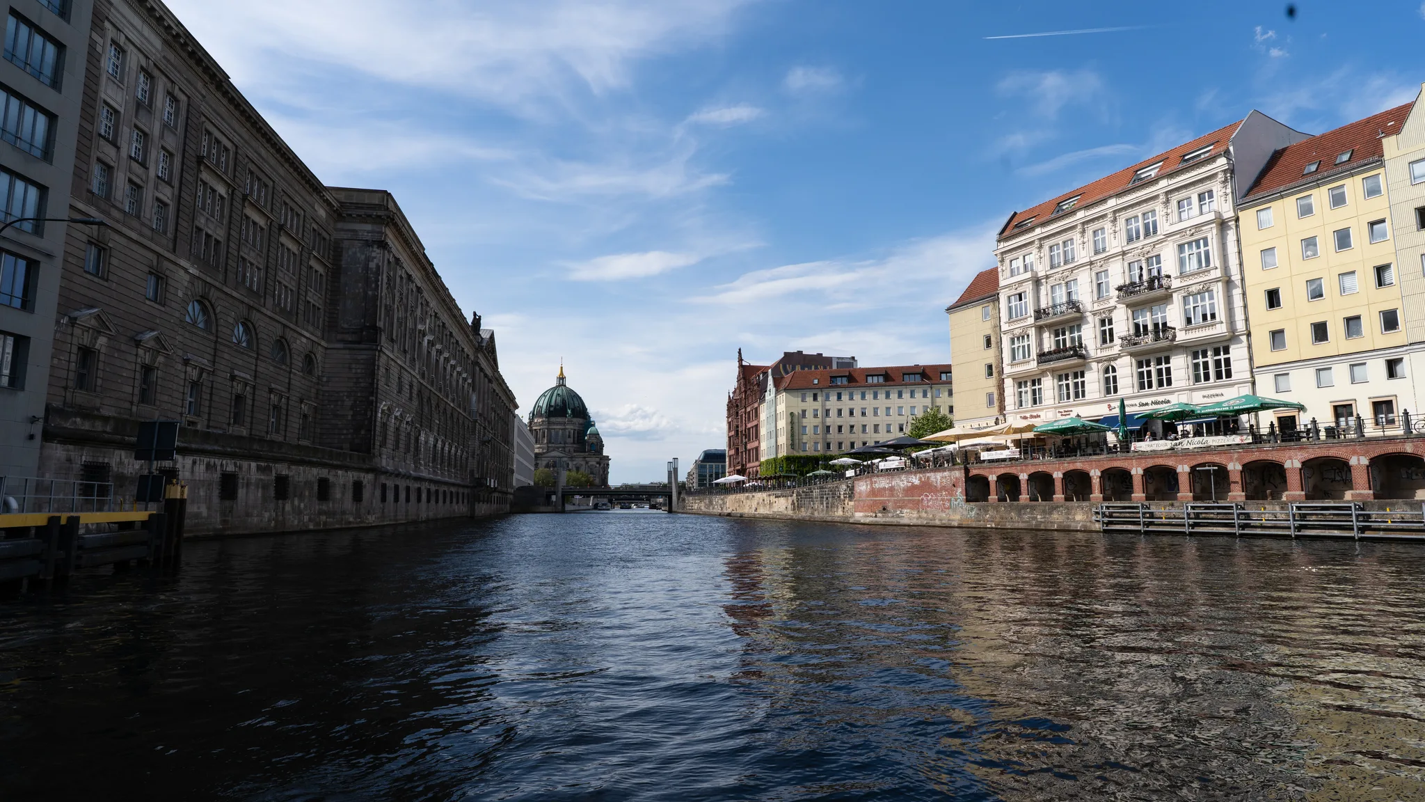 The River Spree with the dome of Berlin Cathedral in the distance and riverside cafés on the right