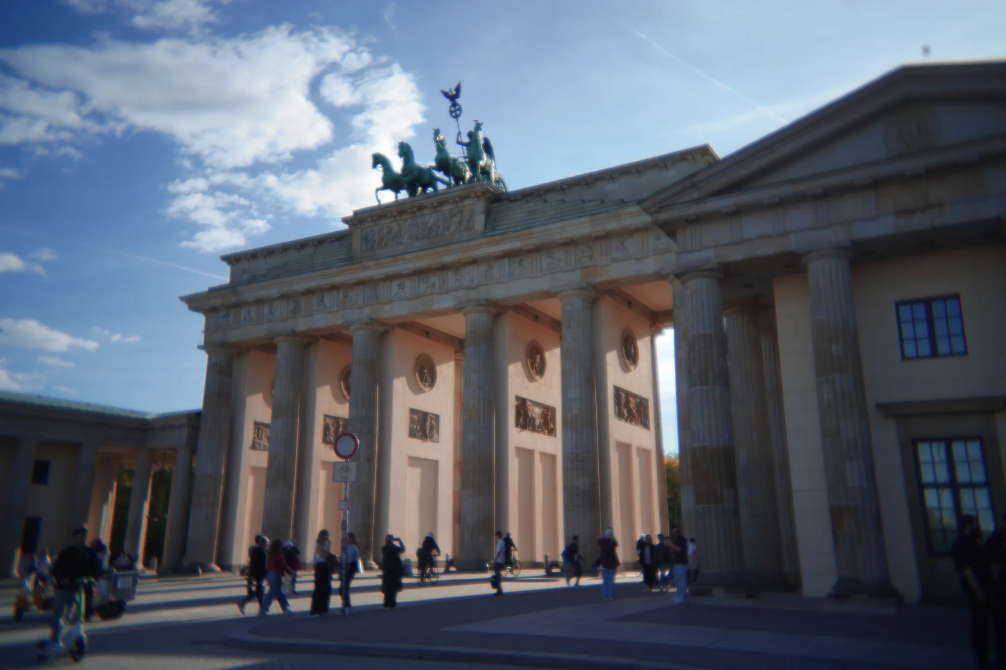 The Brandenburg Gate under a blue sky, with visitors walking between its columns